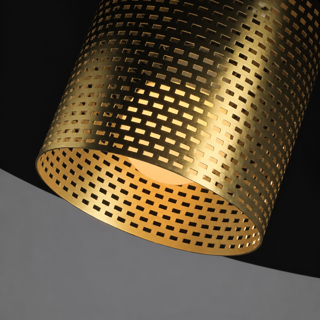 Close view of the illuminated perforated brass cylindrical lamp holder